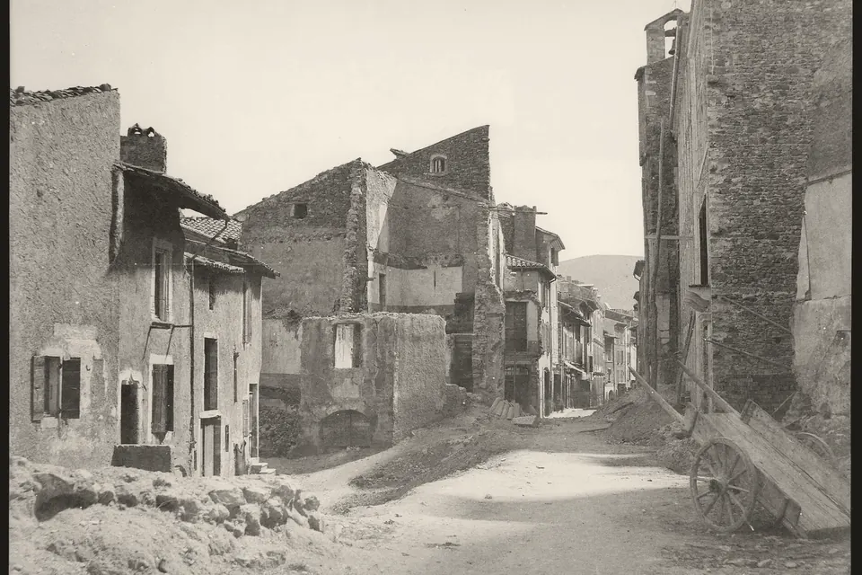 Rue ancienne de Dieulefit bordée de maisons de pierre, dont l'une est en cours de démolition, photographie sur plaque de verre