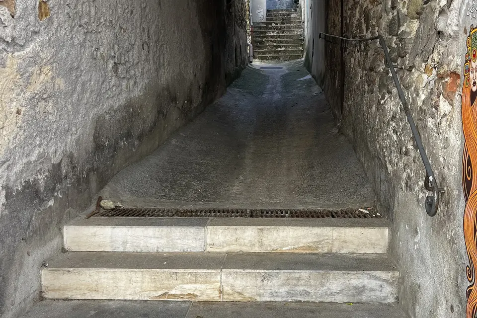 Une ruelle couverte de Dieulefit, étroite et en pente, avec des marches de pierre entre de hauts murs crépis